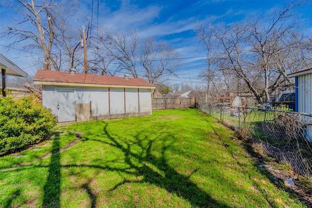 a view of a house with a big yard plants and large tree