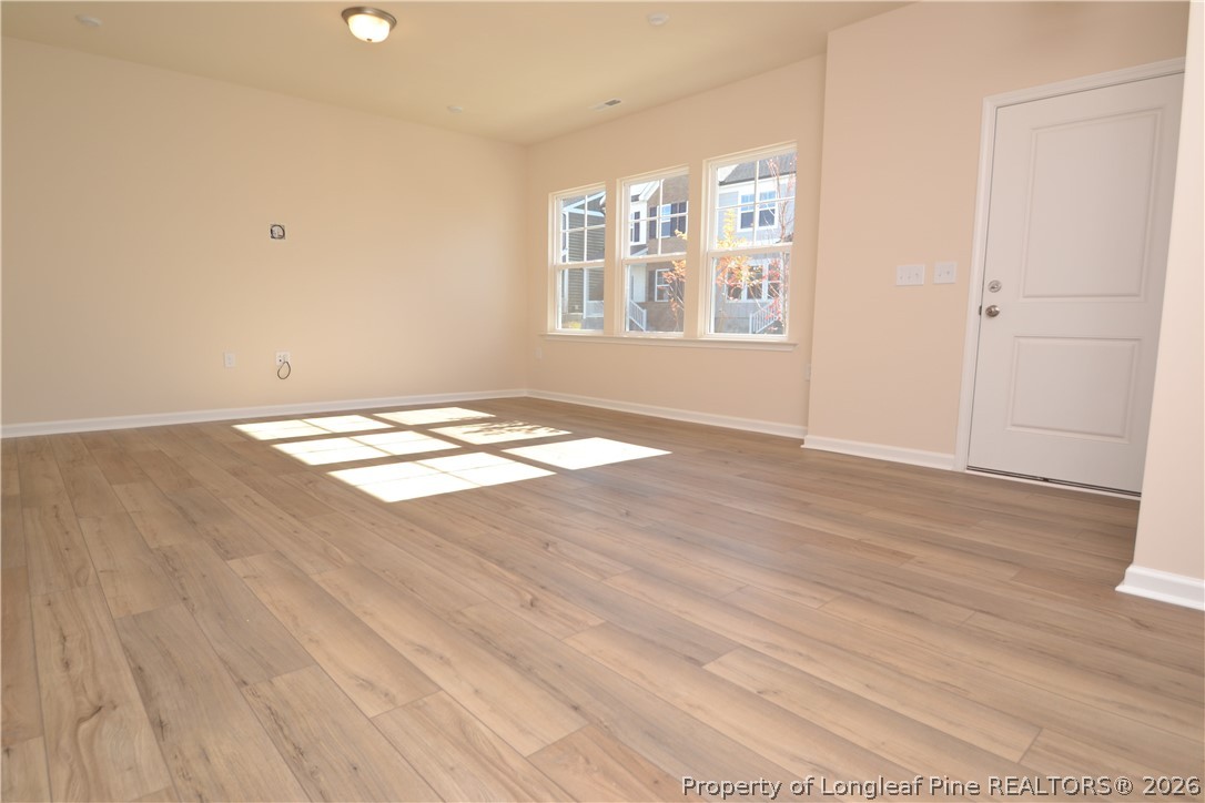 5703 Preveza Place Raleigh, NC 27603 - Photo 5 of 33 an empty room with wooden floor chandelier and windows
