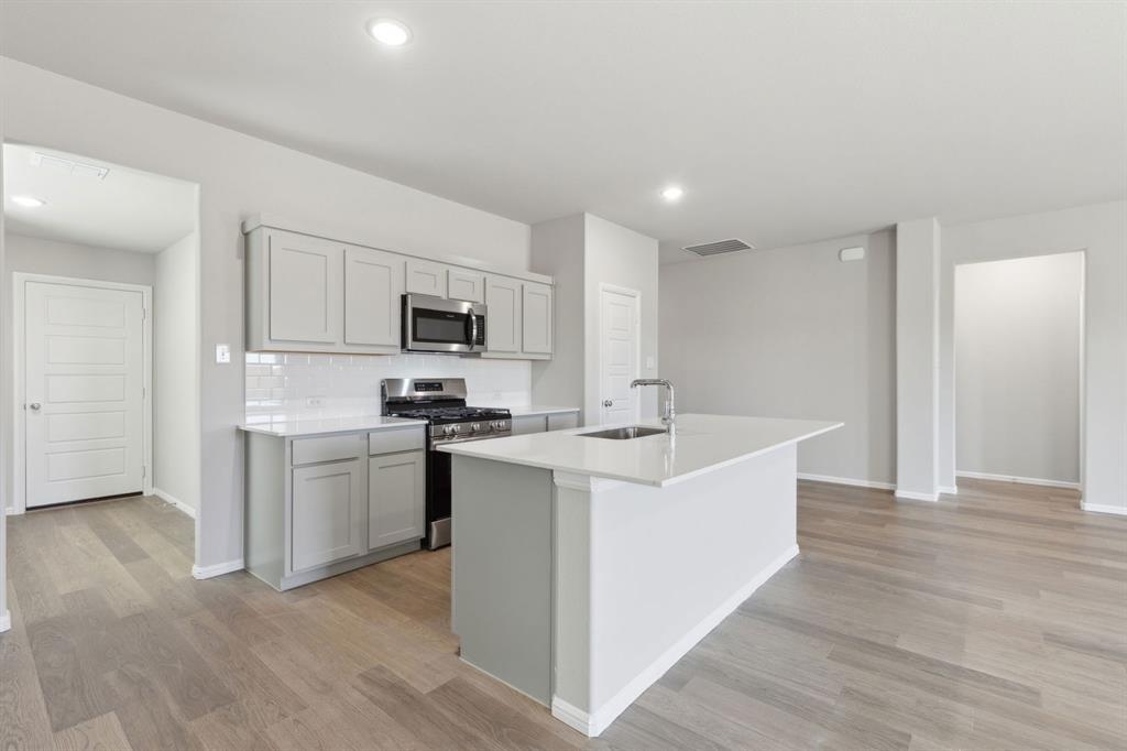 506 River Rdg Drive McKinney, TX 75071 - Photo 6 of 35 a kitchen with white cabinets and stainless steel appliances