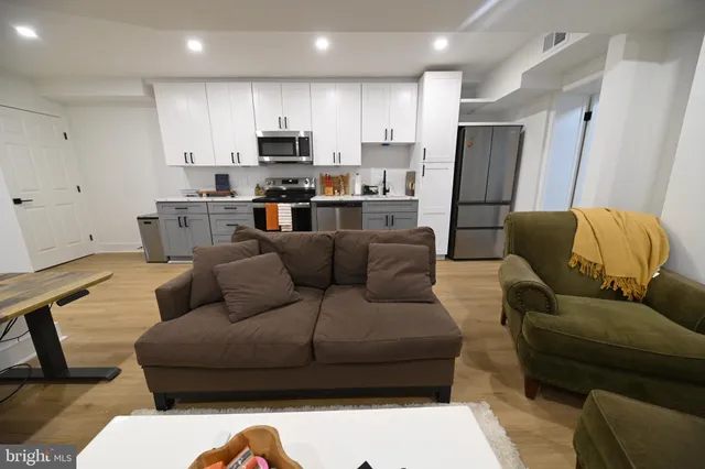 a living room with stainless steel appliances furniture refrigerator and a couch