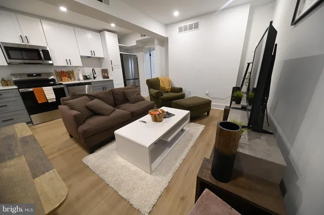 a living room with stainless steel appliances furniture a couch and a flat screen tv