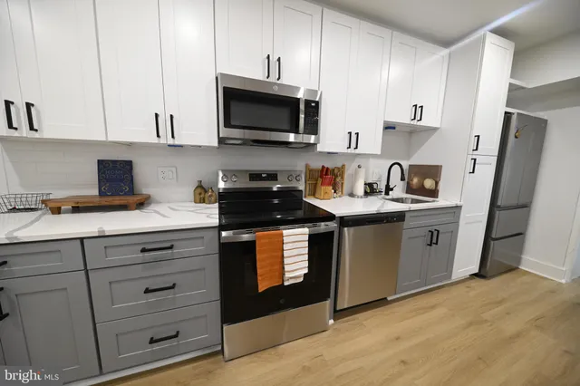 a kitchen with stainless steel appliances granite countertop a stove a sink dishwasher and a microwave oven with white cabinets