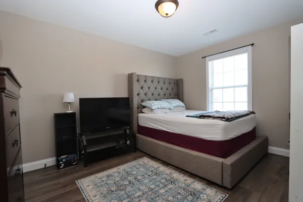 a bedroom with a bed and a flat tv screen on dresser