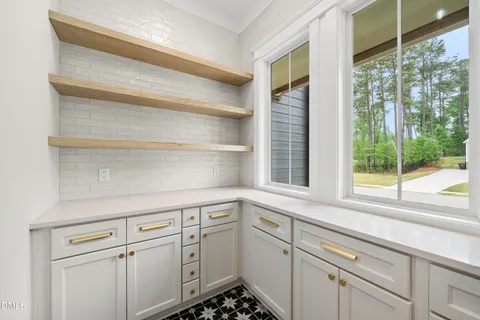 a kitchen with white cabinets and a window