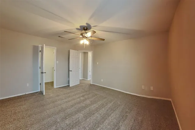 an empty room with a ceiling fan and a window