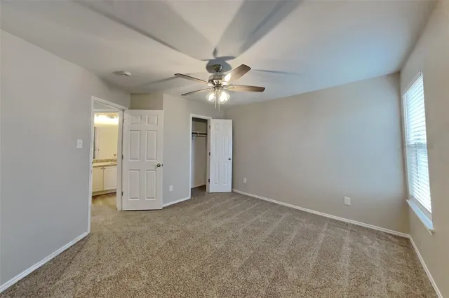 an empty room with chandelier fan and windows