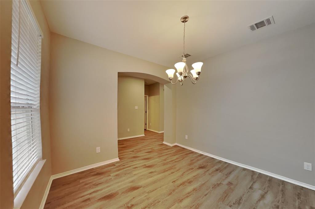 1077 Harriman Drive Saginaw, TX 76131 - Photo 8 of 23 a view of an empty room with wooden floor and a window