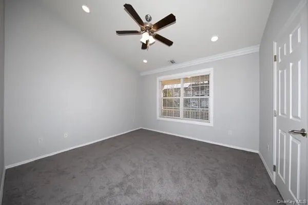 an empty room with ceiling fan and windows