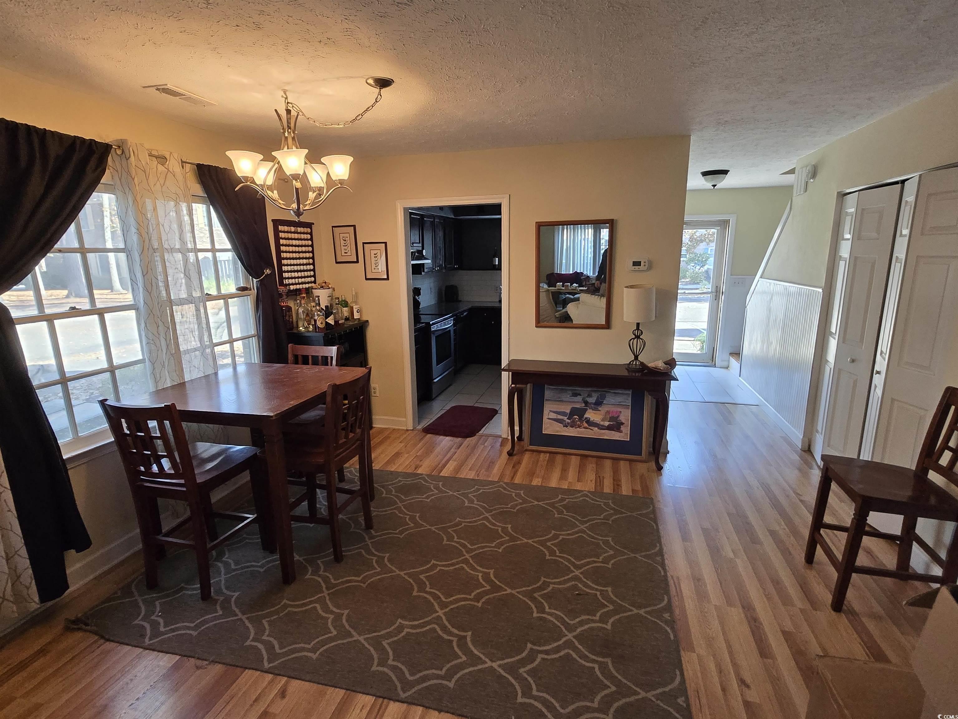 830 44th Avenue North, Unit B4 Myrtle Beach, SC 29577 - Photo 3 of 13 Dining space featuring a textured ceiling, light wood finished floors, plenty of natural light, and a chandelier
