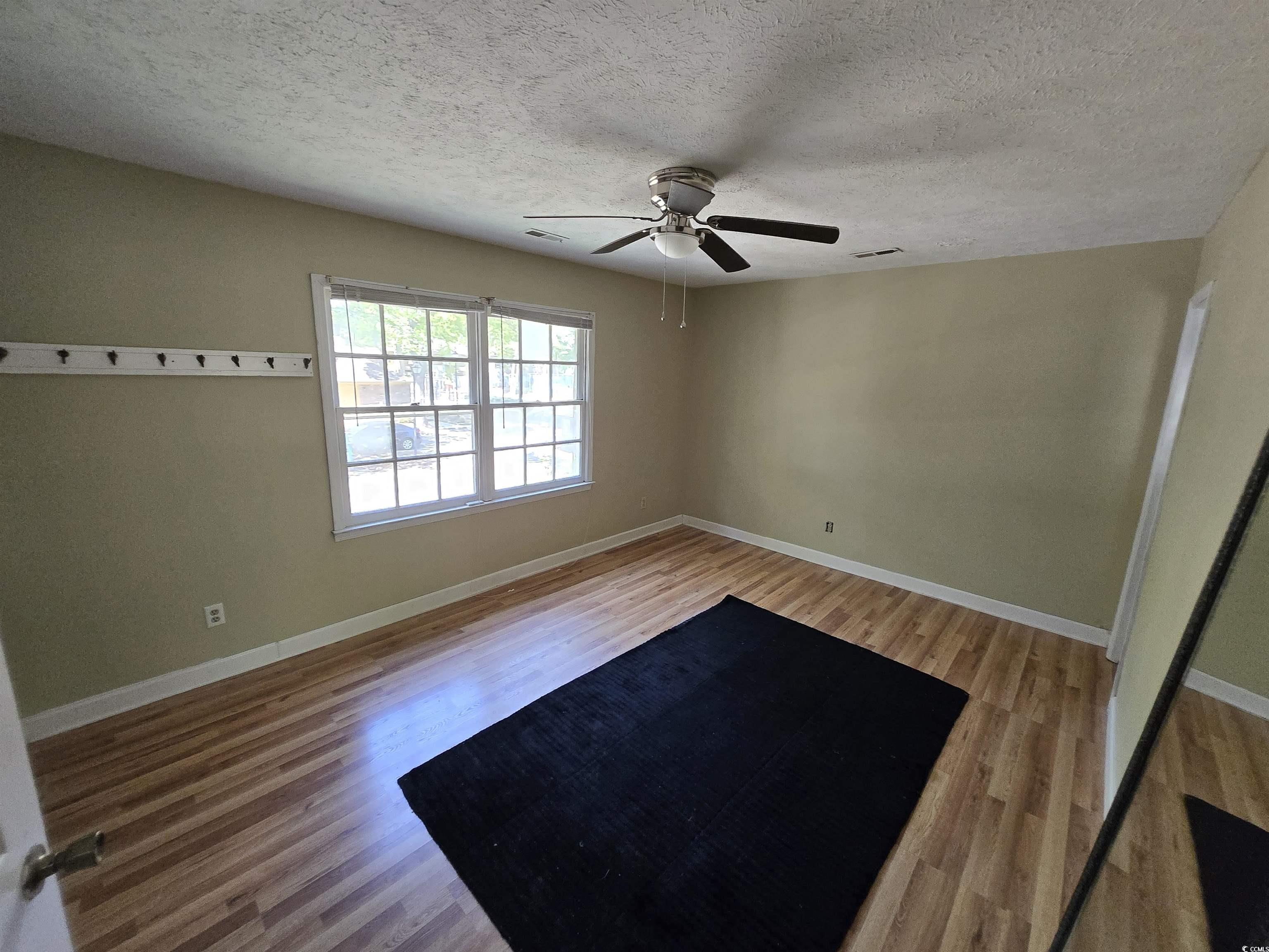830 44th Avenue North, Unit B4 Myrtle Beach, SC 29577 - Photo 6 of 13 Unfurnished room featuring light wood-style flooring, a textured ceiling, and ceiling fan