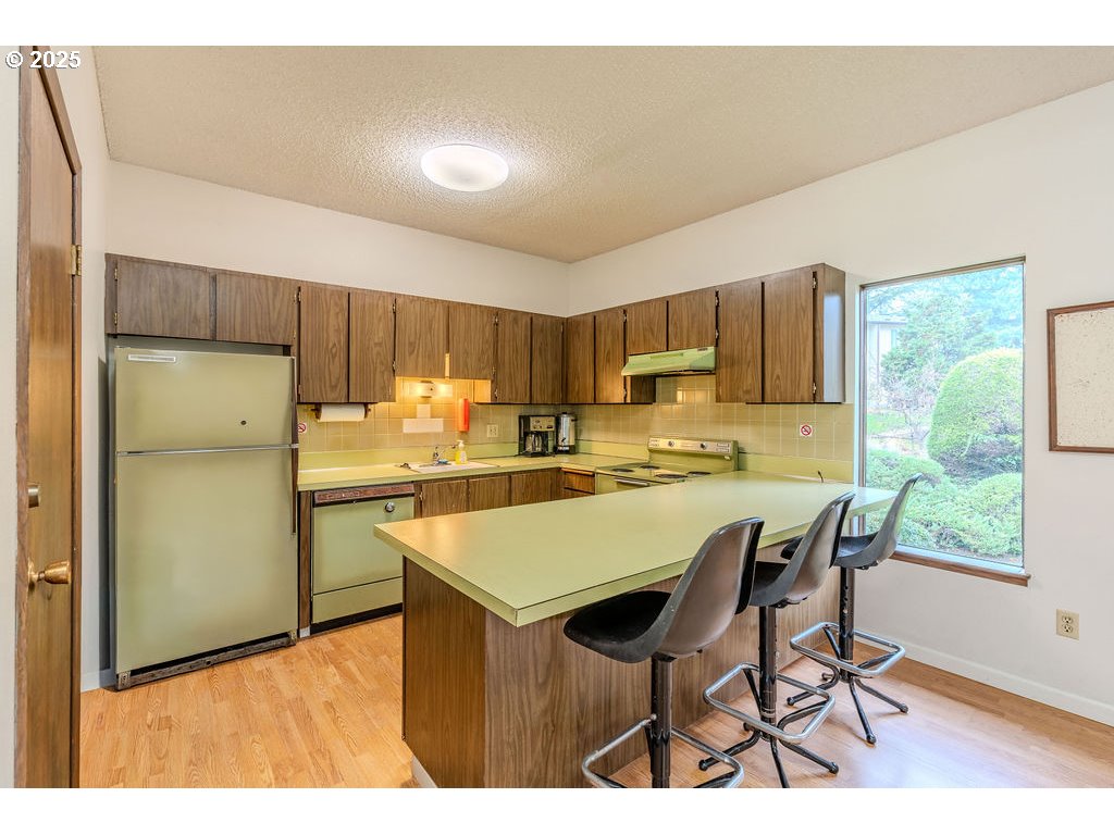 200 Southwest Florence Avenue, Unit D15 Gresham, OR 97080 - Photo 23 of 29 a kitchen with a table chairs refrigerator and cabinets