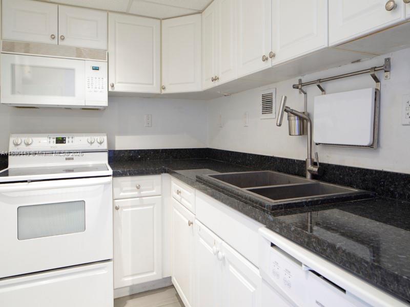 1200 West Avenue, Unit 202 Miami Beach, FL 33139 - Photo 11 of 45 a kitchen with granite countertop white cabinets and white appliances