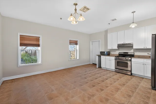 a kitchen with granite countertop a stove a sink a window and stainless steel appliances