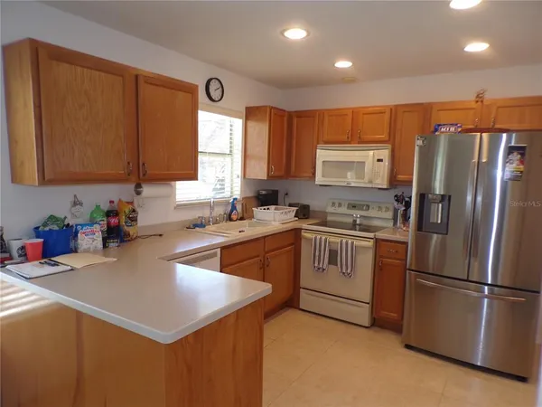 a kitchen with a refrigerator a sink a stove a microwave a counter top and cabinets