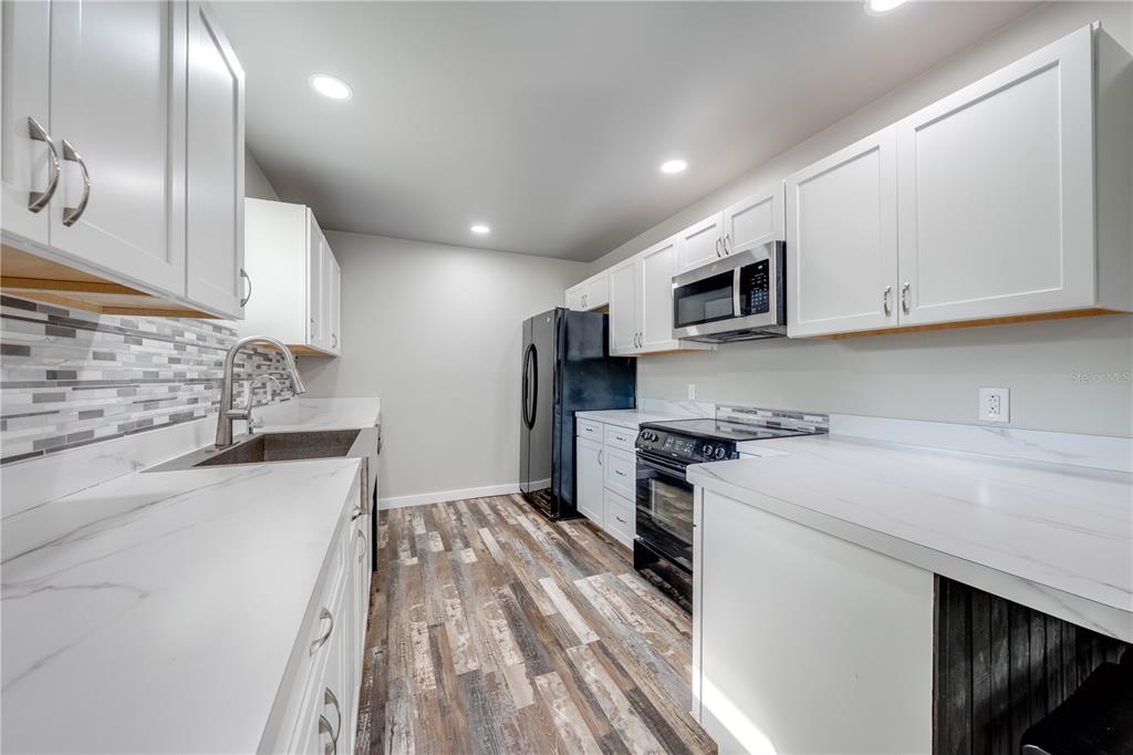 150 North Post Road Kenansville, FL 34739 - Photo 11 of 42 a kitchen with stainless steel appliances granite countertop a stove a sink and a microwave