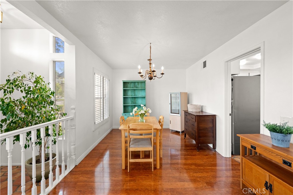 16 Wellesley, Unit 2 Irvine, CA 92612 - Photo 12 of 55 a dining room with wooden floor a chandelier a wooden table and chairs