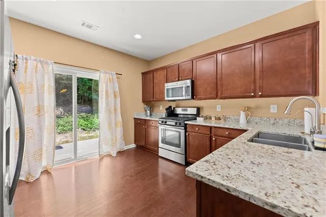 a kitchen with stainless steel appliances granite countertop a stove a sink a refrigerator and a microwave