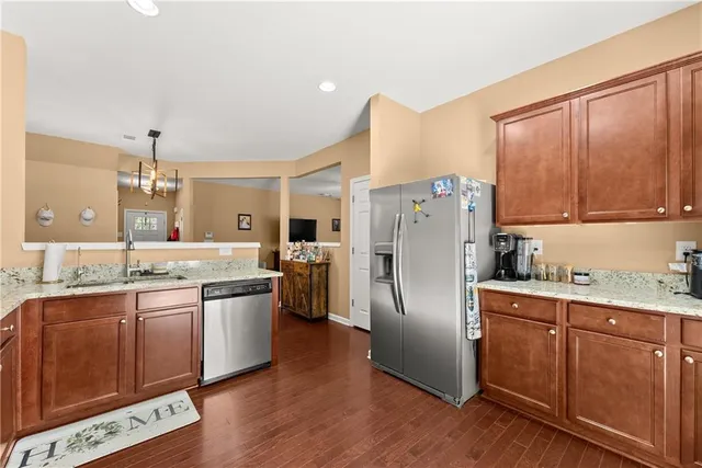 a kitchen with stainless steel appliances granite countertop a refrigerator a sink dishwasher a stove with wooden floor and cabinets