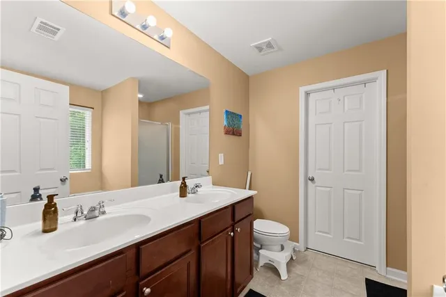 a bathroom with a granite countertop sink a toilet and a large mirror