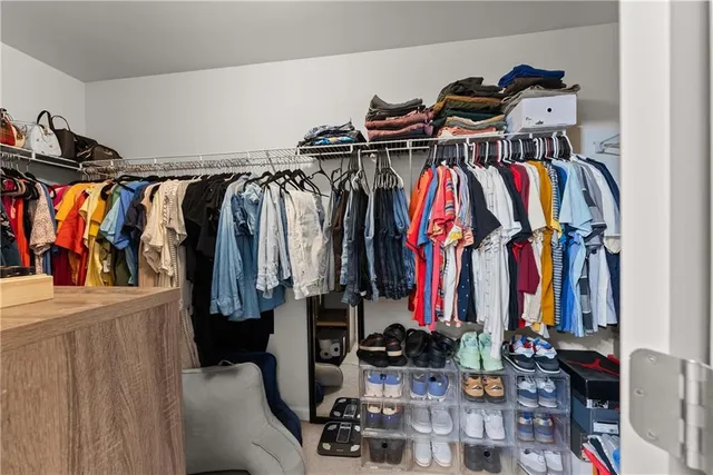 a view of walk in closet with clothes and shoes