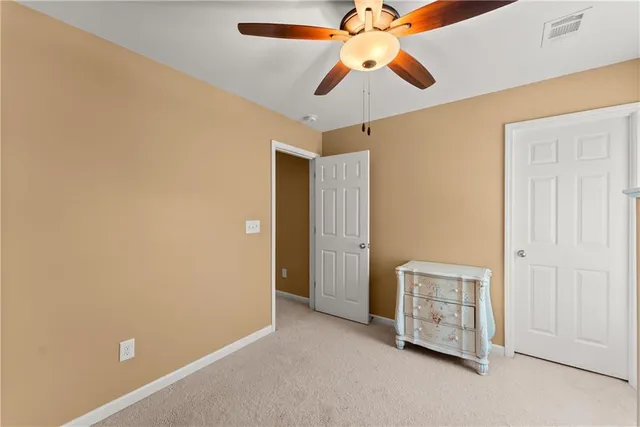 an empty room with closet and a chandelier fan