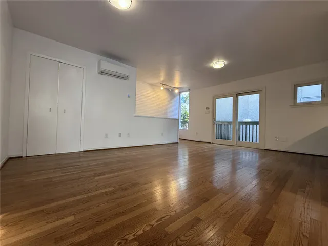a view of an empty room with wooden floor and fan