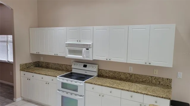 a kitchen with granite countertop white cabinets and a stove