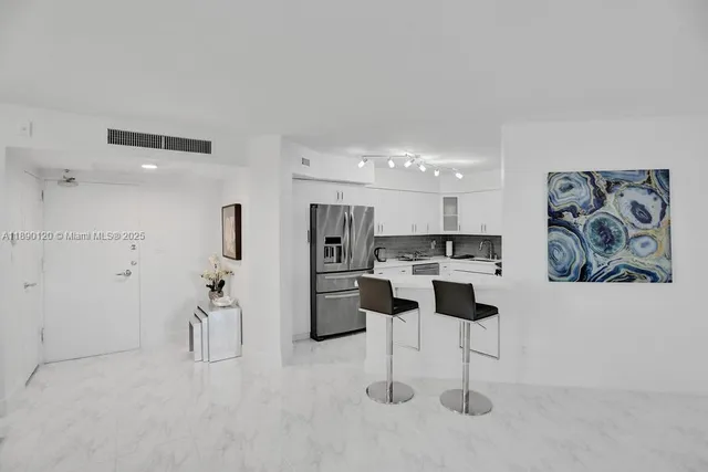 a kitchen with stainless steel appliances kitchen island granite countertop a refrigerator and a sink