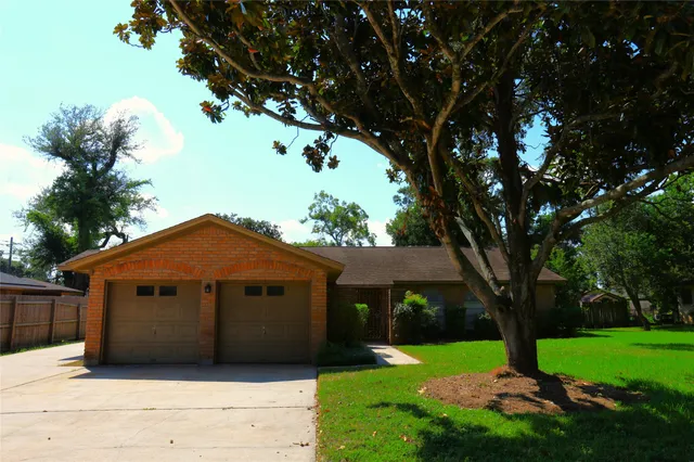 a view of a house with a large tree in front of a yard