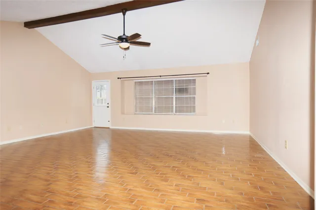 an empty room with wooden floor ceiling fan and windows