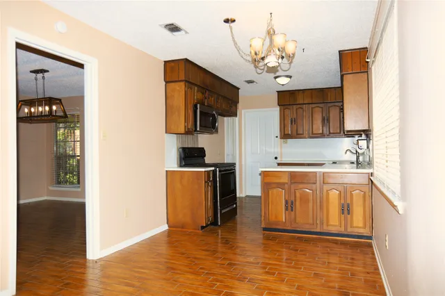 a kitchen with stainless steel appliances granite countertop a refrigerator a sink dishwasher a oven with white cabinets and wooden floor