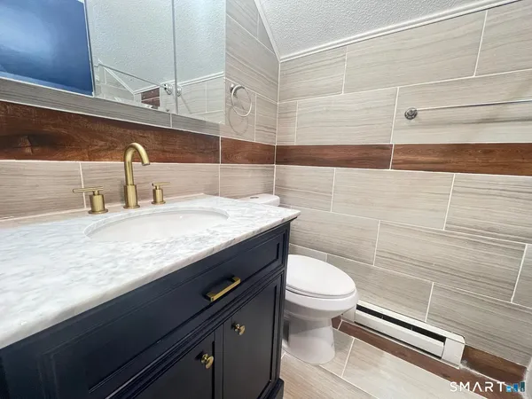 a bathroom with a granite countertop sink a toilet and a mirror