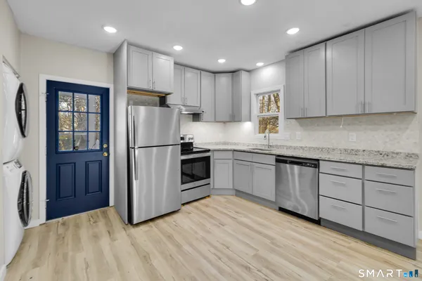a kitchen with granite countertop a refrigerator sink and cabinets