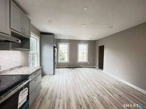 a view of an empty room with a window and wooden floor
