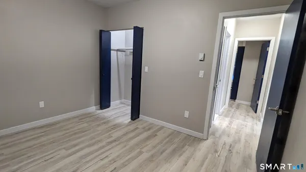 a view of an empty room with wooden floor and a bathroom