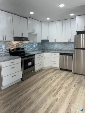 a kitchen with granite countertop wooden cabinets stainless steel appliances and a counter space