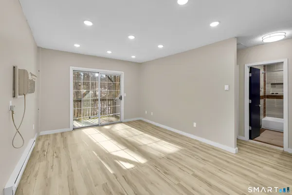 a view of an empty room with wooden floor and a window