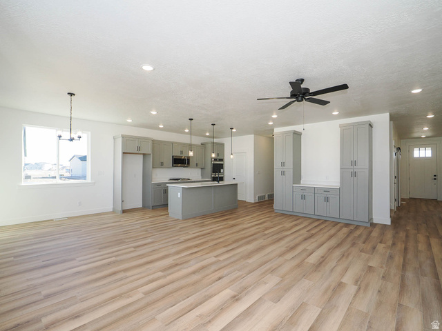 3938 North Wood Road Eagle Mountain, UT 84005 - Photo 53 of 55 Kitchen with gray cabinets, light wood-style floors, light countertops, open floor plan, and a textured ceiling