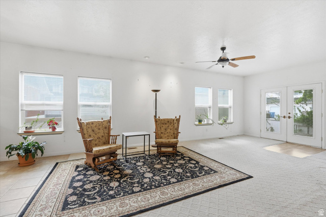 560 East 700 North Logan, UT 84321 - Photo 6 of 32 Spacious room featuring multiple windows, white walls, a ceiling fan with integrated lighting, and French doors providing external access