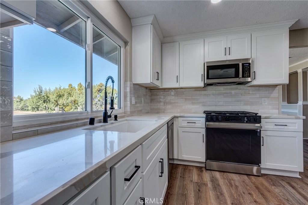 6572 Merced Road Oak Hills, CA 92344 - Photo 17 of 62 a kitchen with stainless steel appliances granite countertop a sink a stove and a wooden floors