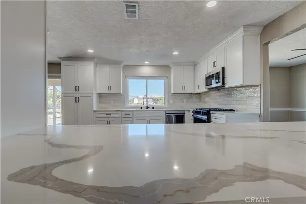 an empty room with ceiling fan and windows