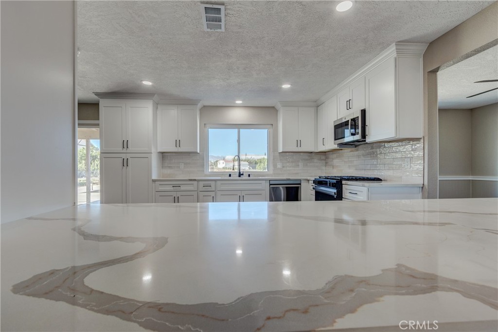 6572 Merced Road Oak Hills, CA 92344 - Photo 22 of 62 a large kitchen with granite countertop a large counter top stainless steel appliances and cabinets