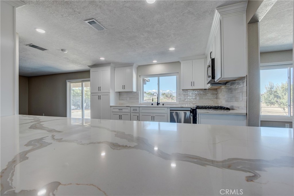 6572 Merced Road Oak Hills, CA 92344 - Photo 23 of 62 a large white kitchen with kitchen island a sink stainless steel appliances and cabinets