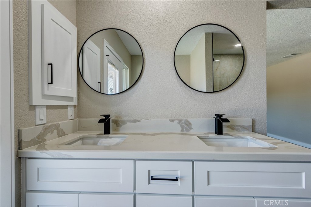 6572 Merced Road Oak Hills, CA 92344 - Photo 38 of 62 a bathroom with a granite countertop a sink and a mirror