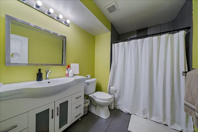a bathroom with a sink a toilet a mirror and shower curtain