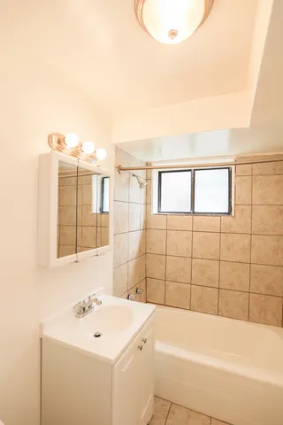 a bathroom with a sink a bathtub and next to a window