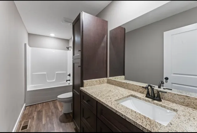 a bathroom with a granite countertop sink toilet and shower