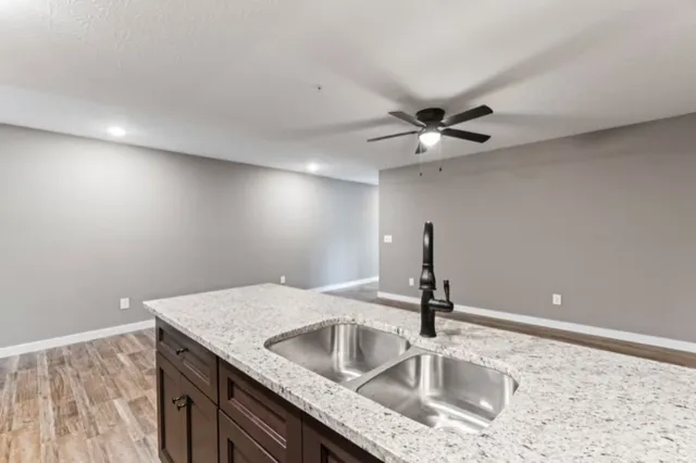 a kitchen with a sink dishwasher and a stove top oven with wooden floor