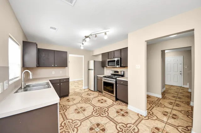 a kitchen with stainless steel appliances kitchen island granite countertop a sink stove and refrigerator