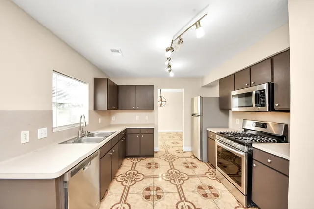 a kitchen with stainless steel appliances kitchen island granite countertop a sink stove cabinets and refrigerator